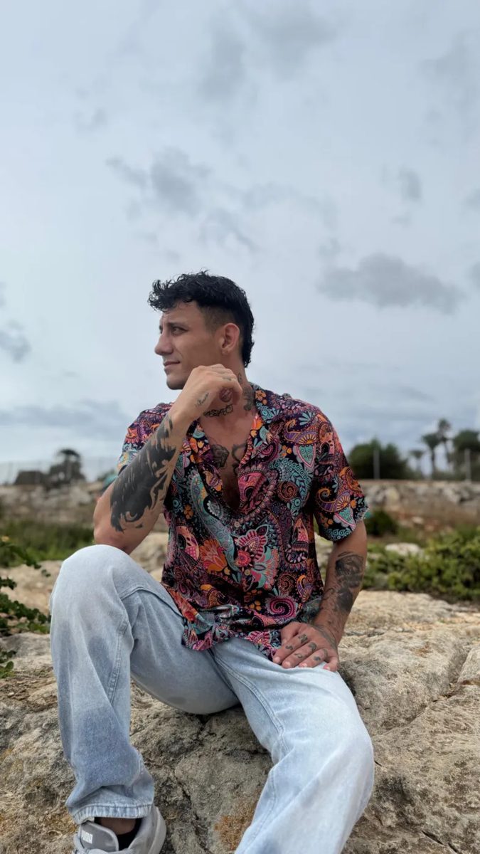 Man in a Retro shirt on a rock by the sea